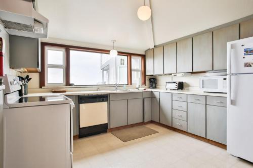 a kitchen with white cabinets and a white refrigerator at Abalone Alcove! Hot Tub! Pool Table! AMAZING VIEWS! Fast WiFi!! Dog Friendly! in Dillon Beach
