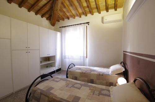 a small room with two beds and a window at Il Torrino in Barberino di Val dʼElsa