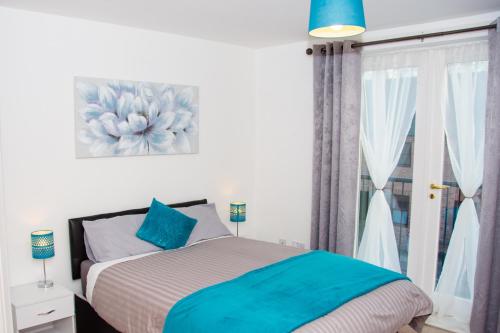 a bedroom with a bed with blue pillows and a window at Grand Central Friar Gate Deluxe Apartments in Derby