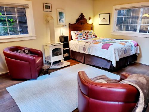 a bedroom with a bed and a couch and chairs at Guerneville Cottage! Redwoods! Hot Tub! Fire Table! Fast WiFi!! Serenity Defined! in Guerneville