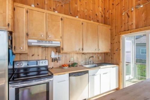 a kitchen with wooden cabinets and a stove top oven at Breaking Waves! On the Bluff! AMAZING VIEWS!! BBQ! Fast WiFi! Walk to Beach!!! in Dillon Beach