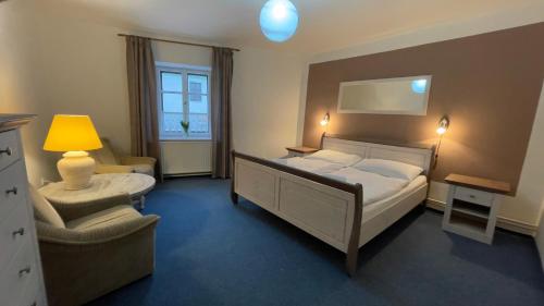 a bedroom with a large bed and a chair at Pension Linden in Český Krumlov