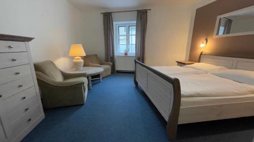 a bedroom with a bed and a chair and a dresser at Pension Linden in Český Krumlov