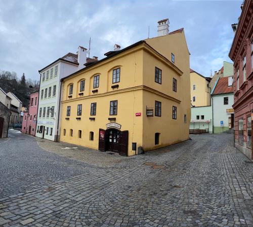 a large yellow building on a cobblestone street at Pension Linden in Český Krumlov