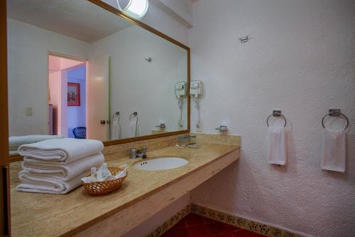 a bathroom with a sink and a mirror and towels at Costa Sur All Inclusive Resort in Puerto Vallarta