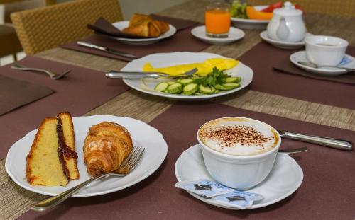 a table with plates of food and a cup of coffee at Hotel Vittoria in Viareggio