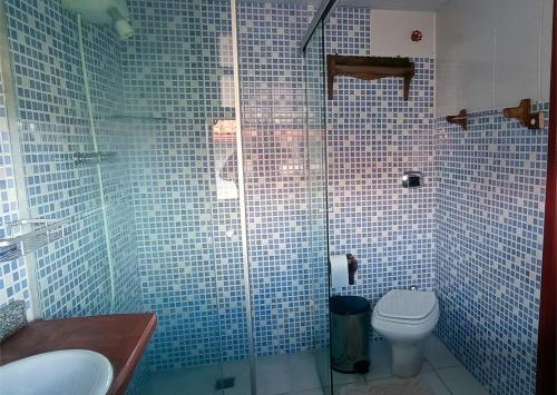 a bathroom with a toilet and a glass shower at Pousada Solar dos Anjos in Lavras Novas