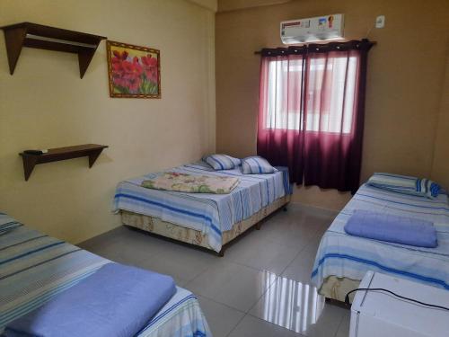 a bedroom with two twin beds and a window at Pousada M&atilde;e Ternura palace in Aparecida