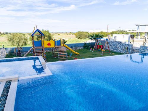 a swimming pool with a slide and a playground at Aphrodite Beachfront Resort Official in Ghaziveran