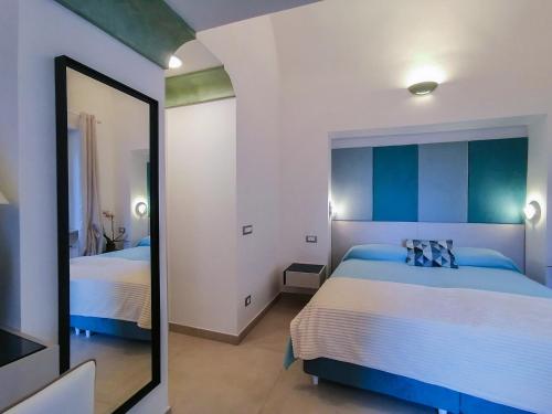 a bedroom with two beds and a mirror at Atrani Rooms in Atrani