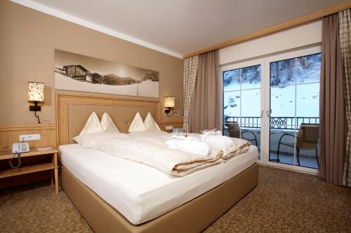 a hotel room with a bed and a balcony at ZillergrundRock Luxury Mountain Resort in Mayrhofen