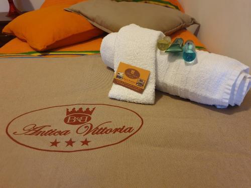 a hotel room with a bed with towels and a sign at Antica Vittoria in Vittoria