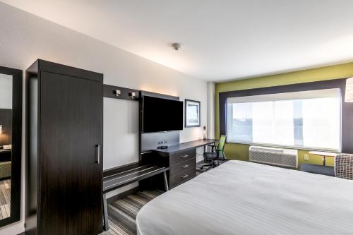 a bedroom with a bed and a desk with a television at Holiday Inn Express & Suites Jersey City North - Hoboken by IHG in Jersey City