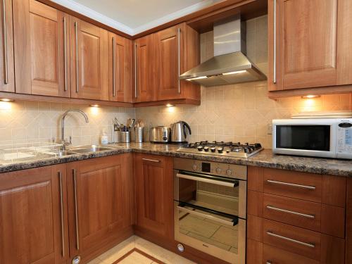 a kitchen with wooden cabinets and a stove and microwave at 2 Embankment House in Dartmouth