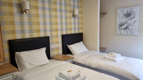 2 camas en una habitación con sábanas blancas y toallas en The Aston Inn en Birmingham