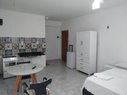 Habitación con cama, mesa y cocina. en Flat 302 en Ubá