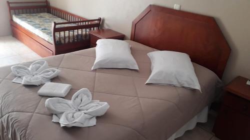 a bed with white pillows and towels on it at Apartamentos Sulla Collina Centro de Gramado localizado próximo da rua Coberta in Gramado