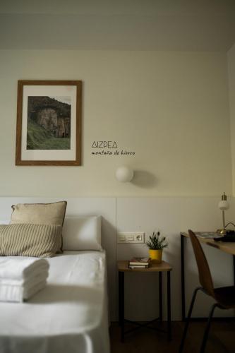 a bedroom with a bed and a table and a picture at HOTEL ORDIZIA in Villafranca de Ordizia