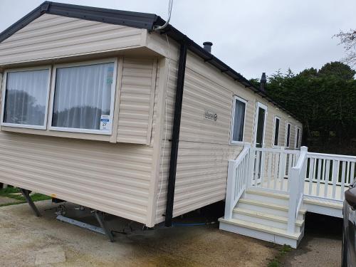 a mobile home with a porch and a white railing at 3 Bedroom Caravan, Sleeps 8, at Parkdean Newquay Holiday Park in Newquay