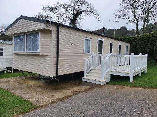 a mobile home with a white porch and stairs at 3 Bedroom Caravan, Sleeps 8, at Parkdean Newquay Holiday Park in Newquay