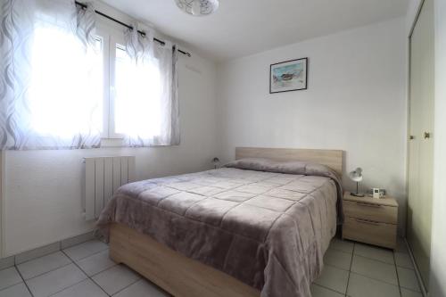 une chambre avec un grand lit et une fenêtre dans l'établissement RESIDENCE LE NEULOS, T2 40m2 AVEC GARAGE PRIVE, 150 m de la mer, Avenue Roussillon Canet-Plage, à Canet
