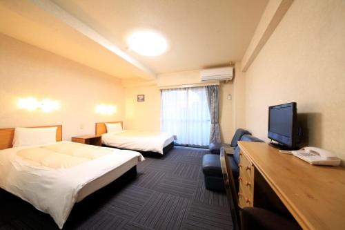 a hotel room with two beds and a flat screen tv at Monthly Mansion Tokyo West 21 - Vacation STAY 10884 in Fuchu