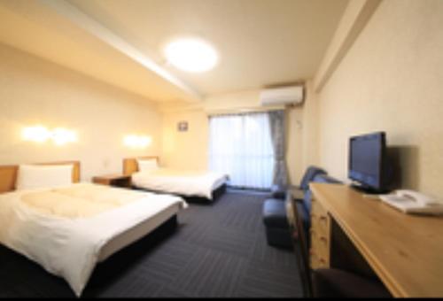 a hotel room with two beds and a flat screen tv at Monthly Mansion Tokyo West 21 - Vacation STAY 10889 in Fuchu