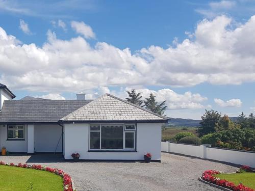 a white house with a gravel driveway at Mountain View Holiday Home by Trident Holiday Homes in Louisburgh