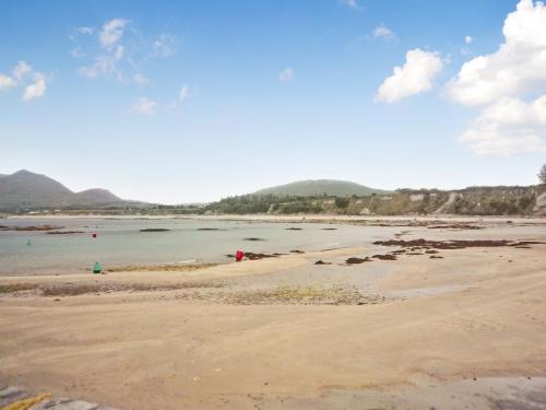 a sandy beach with people in the water at Mountain View Holiday Home by Trident Holiday Homes in Louisburgh