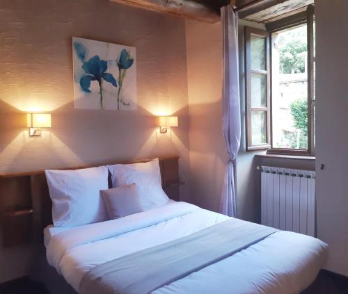 Schlafzimmer mit einem Bett mit weißer Bettwäsche und einem Fenster in der Unterkunft Auberge Cevenole in Valleraugue