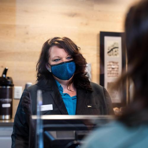 a woman wearing a mask in front of a mirror at Country Inn & Suites by Radisson, BWI Airport Baltimore , MD in Linthicum Heights