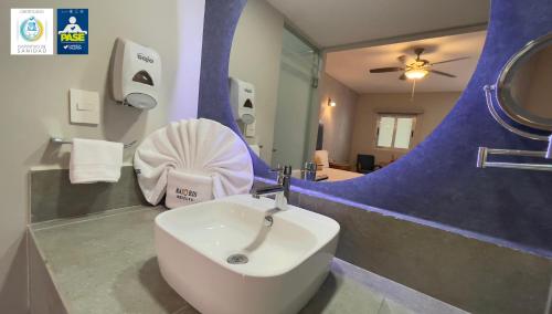 a bathroom with a white sink and a mirror at Hotel Maioris Bellavista in Culiacán