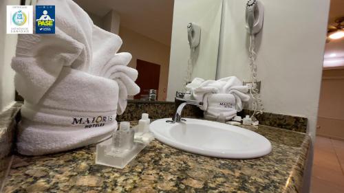 a bathroom with a sink and towels on a counter at Hotel Maioris Navolato in San Pedro