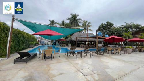 a patio with chairs and tables and umbrellas next to a pool at Hotel Maioris Navolato in San Pedro