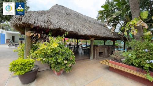 a restaurant with a thatched roof and tables and plants at Hotel Maioris Navolato in San Pedro