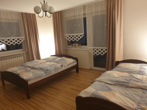 two beds in a room with two windows at Noclegi w gorcach in Ponice