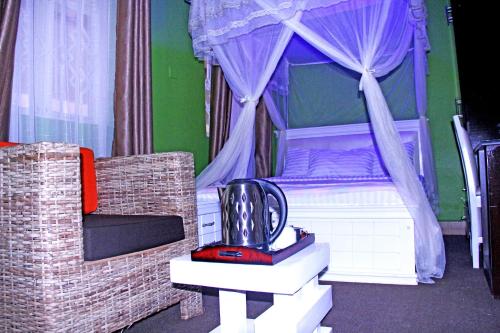 a bedroom with a bed with a canopy and a chair at Bethel Resort & Hotels in Gulu
