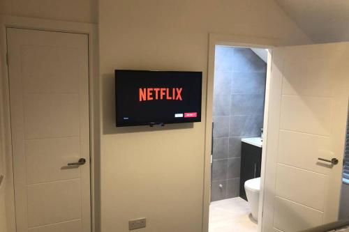 a bathroom with a television on the wall next to a toilet at Oole 2 bed & en-suites house with parking near beach in Cleethorpes