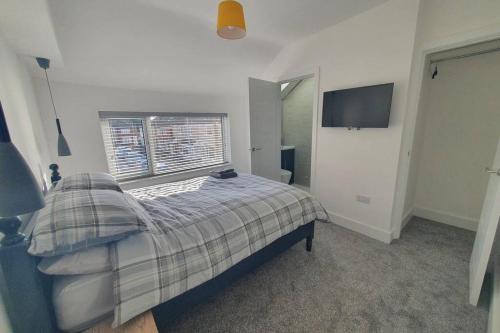 a bedroom with a bed with a plaid blanket and a window at Oole 2 bed & en-suites house with parking near beach in Cleethorpes