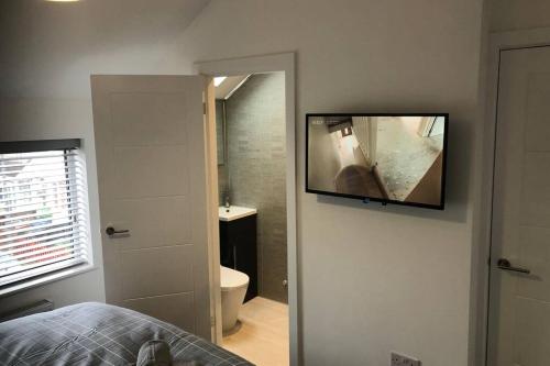 a bedroom with a bathroom with a television on the wall at Oole 2 bed & en-suites house with parking near beach in Cleethorpes