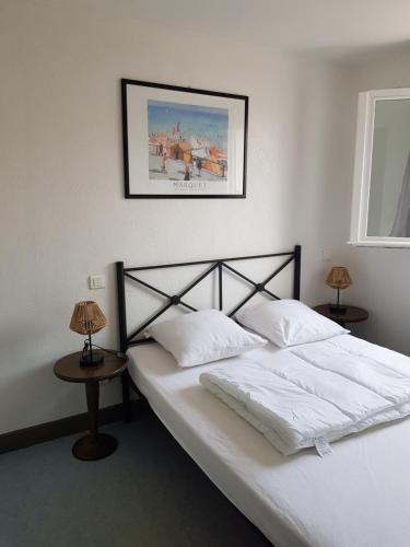 - une chambre avec un lit avec des draps blancs et 2 lampes dans l'établissement Maison cosy au bord de la mer, au Barcarès