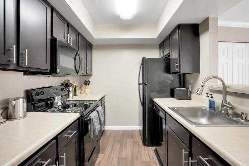 eine Küche mit schwarzen Schränken und einem schwarzen Kühlschrank in der Unterkunft Kasa Downtown Louisville in Louisville