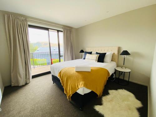 a bedroom with a large bed with a large window at Lake Views at Antler Lodge in Lake Tekapo