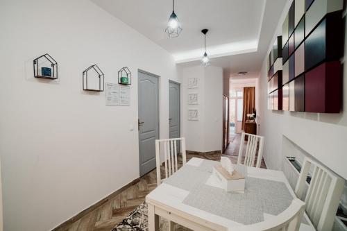 a white dining room with a table and chairs at Garden Apartament Petrila in Petrila