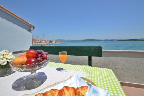a table with a bowl of fruit and a glass of orange juice at Apartments Denko - right on the beach in Betina