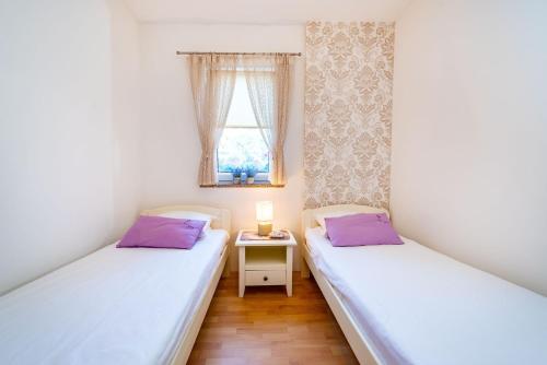 two twin beds in a room with a window at Apartments San - great location in Povljana
