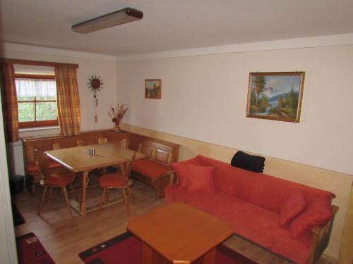 a living room with a red couch and a table at Ferienwohnung Öderhof in Saaldorf