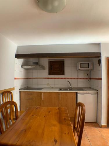 cocina con mesa de madera con sillas y fregadero en Casa La Fragua en La Hiruela