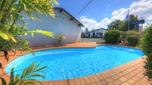 a blue swimming pool in front of a house at Grafton Lodge Motel in Grafton