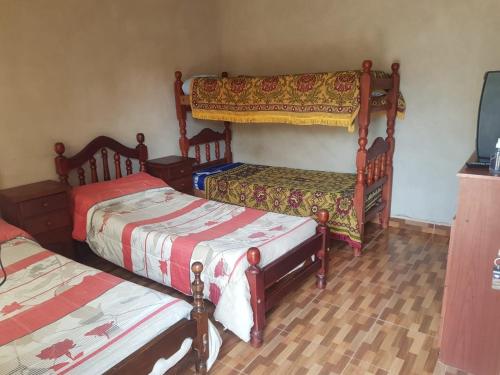 a bedroom with two beds and a tv in it at Hostel Casa de Familia in Humahuaca